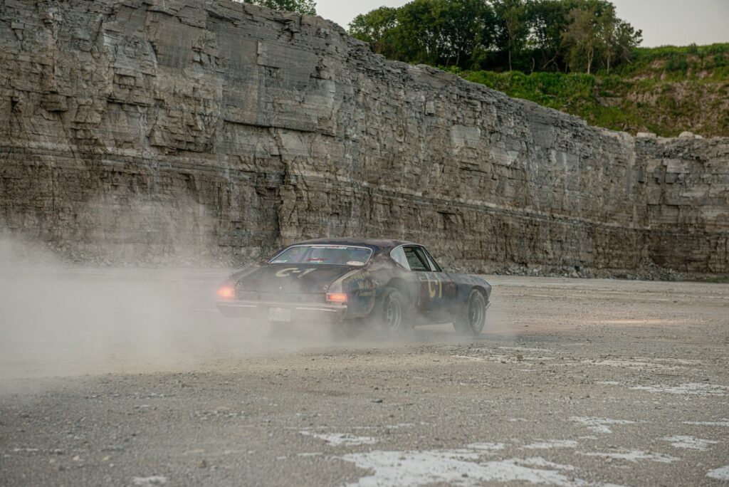 Rear view of 1968 Chevrolet Chevelle driving through dust in quarry