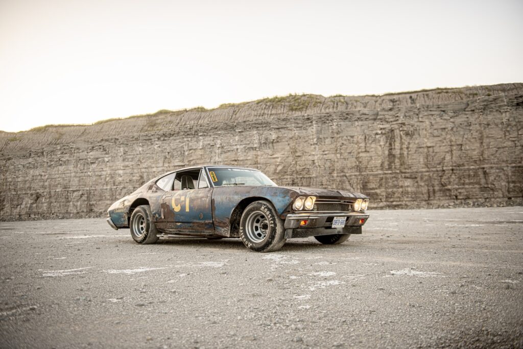 Side profile of weathered 1968 Chevrolet Chevelle race car parked on gravel