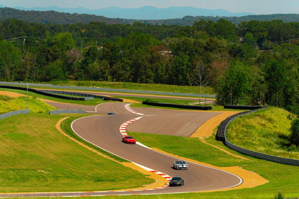 Multiple performance cars driving through an elevation change on a racetrack