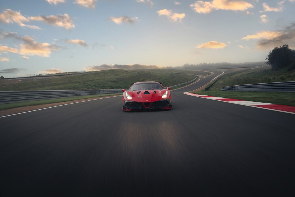 Red Ferrari driving at speed on a racetrack at sunrise or sunset