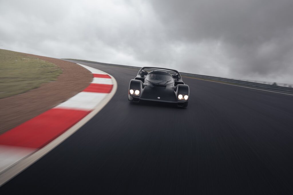 Black prototype-style race car driving through a foggy racetrack corner