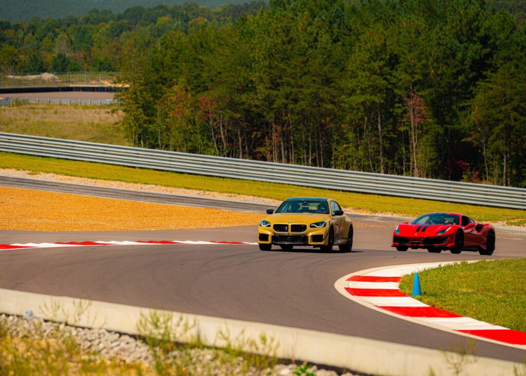 Yellow BMW performance coupe followed by a red Ferrari on racetrack corner