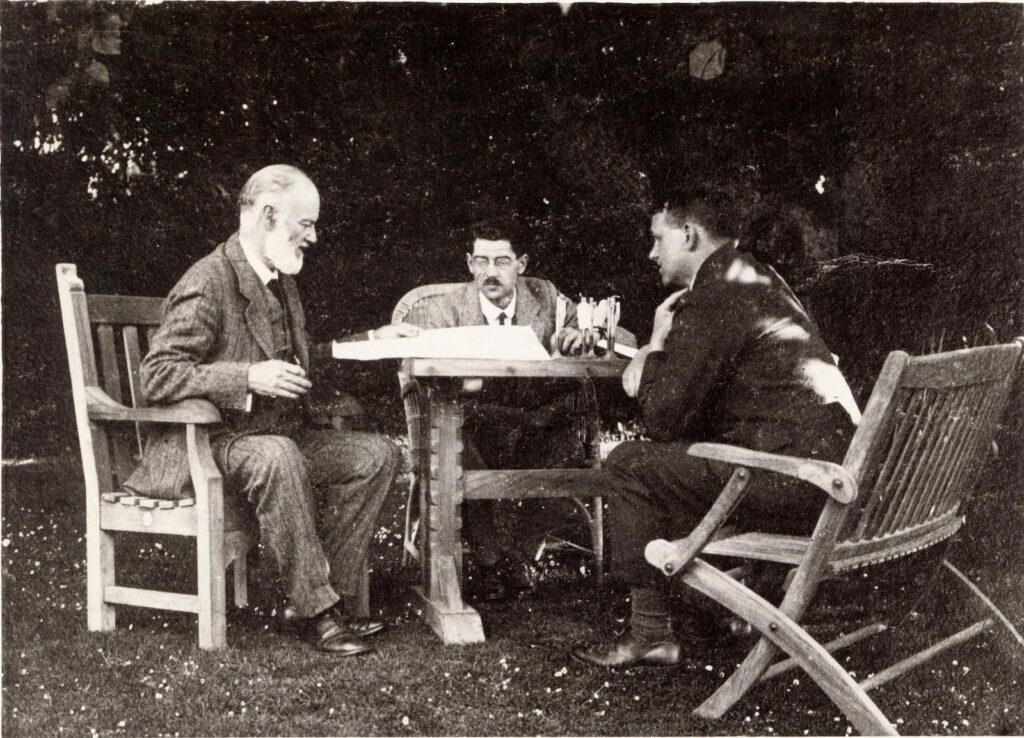Henry Royce seated outdoors at a table beneath a mulberry tree with colleagues