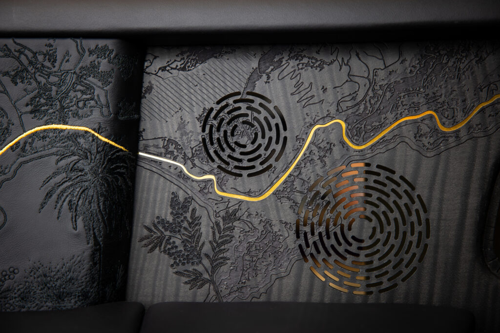 Finished wood panel with gold inlay line and patterned speaker grilles installed