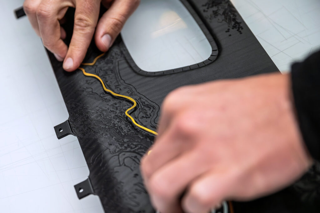 Artisan shaping a gold inlay line into sculpted Rolls-Royce wood veneer