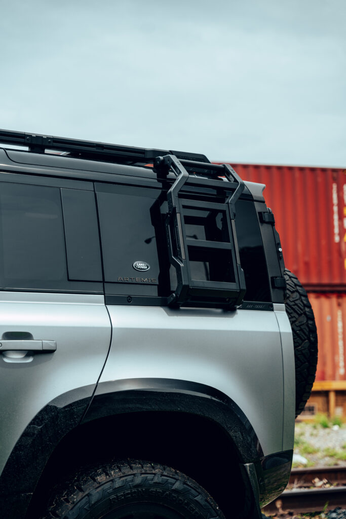Rear quarter view of Artemis Automotive Land Rover Defender with side ladder and roof rack system