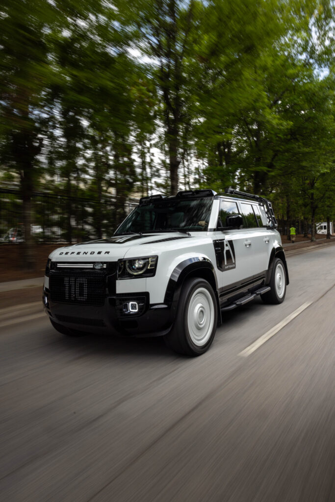 Artemis Automotive Land Rover Defender driving on tree-lined road in motion