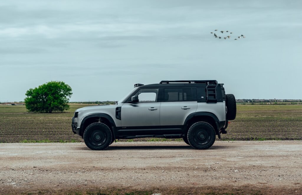 Side profile of Artemis Automotive Land Rover Defender parked on rural dirt road