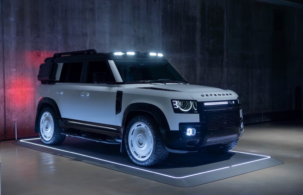 White Artemis Automotive Land Rover Defender displayed on illuminated studio platform