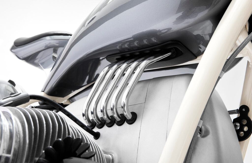 Close-up of polished exhaust header pipes flowing beneath the fuel tank on the custom BMW R75/5