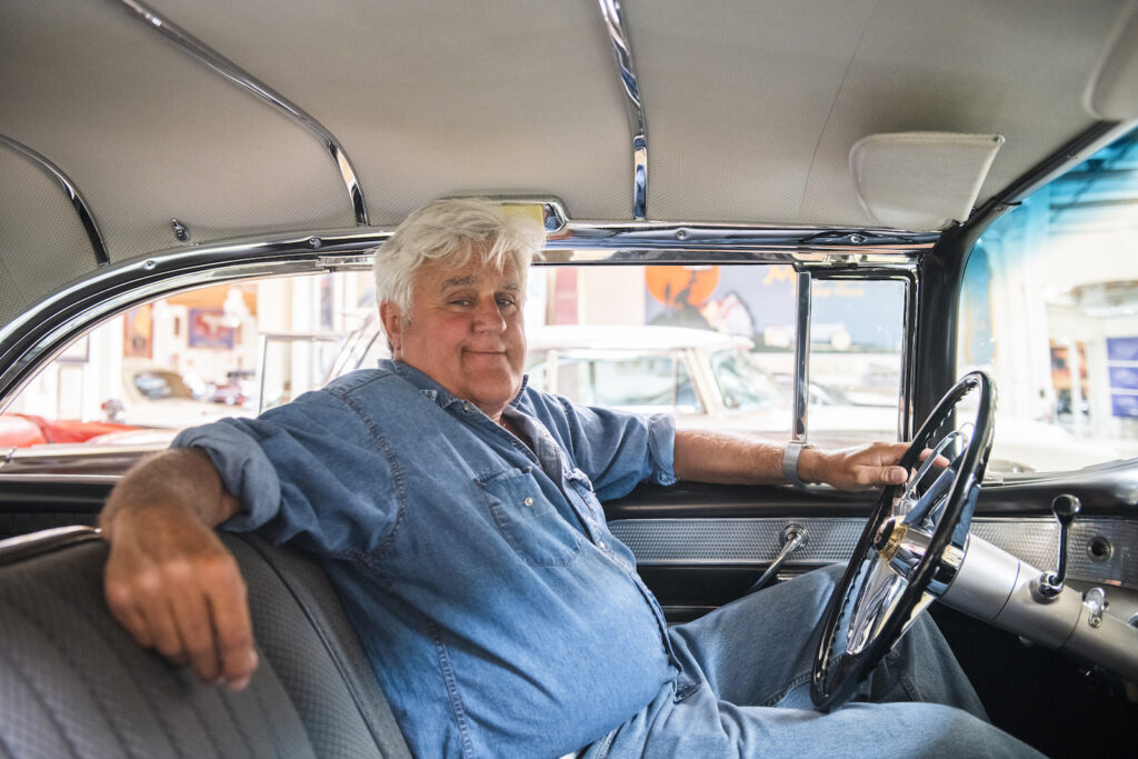 Jay Leno sitting inside classic car