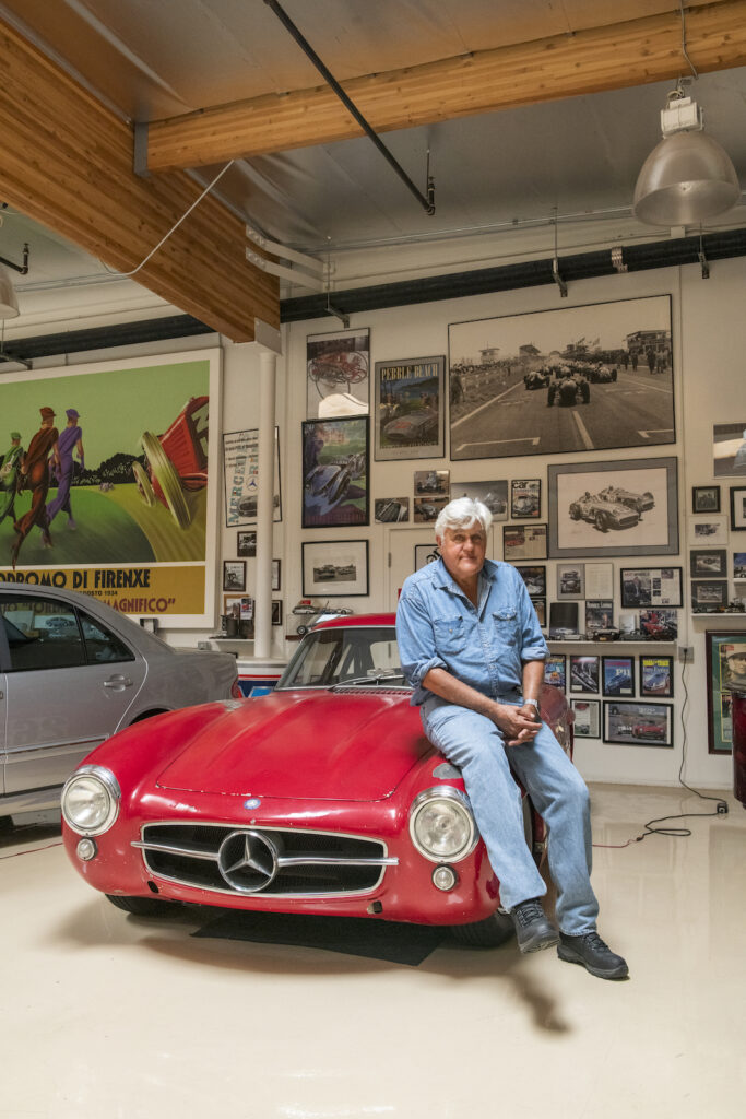 Jay Leno sitting on red Mercedes roadster