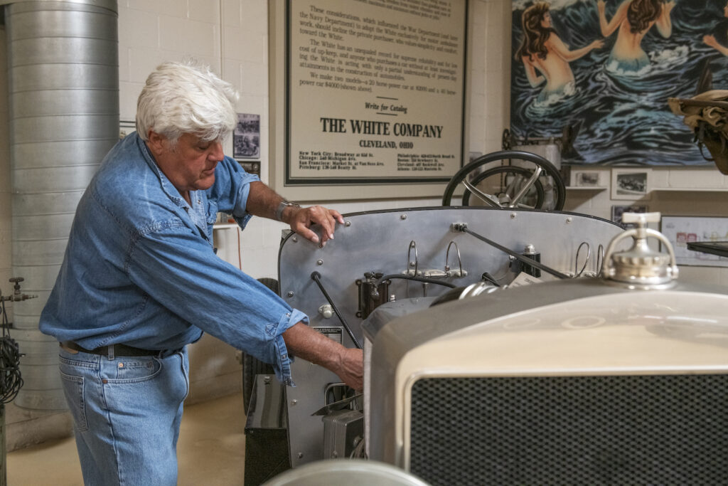 Jay Leno looks at vintage car in garage
