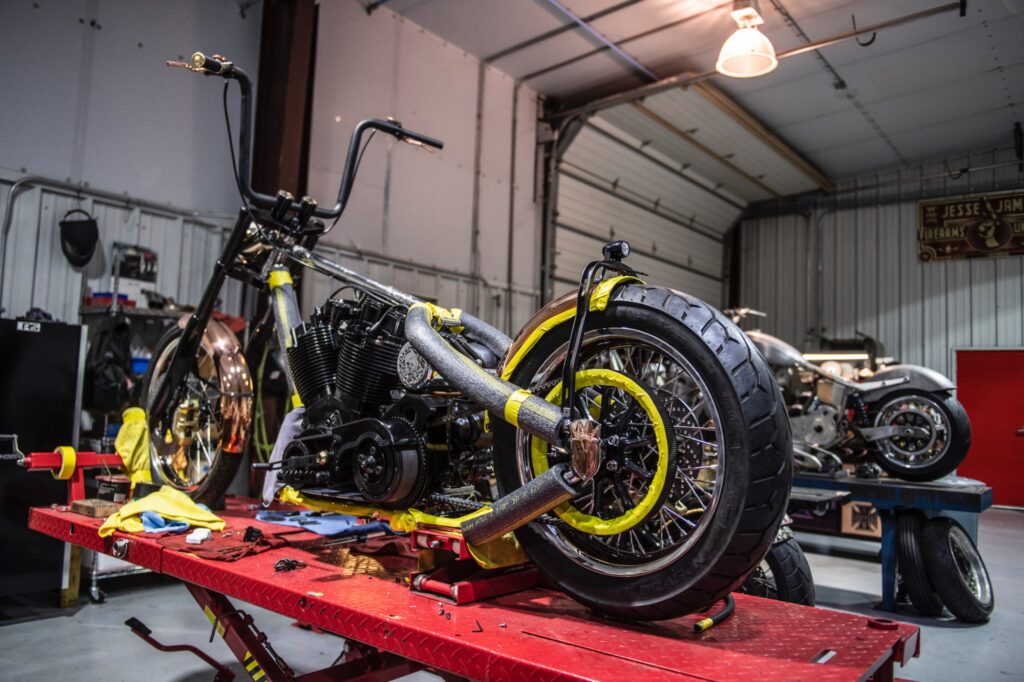 Custom chopper motorcycle on hydraulic lift inside Jesse James’ Texas workshop