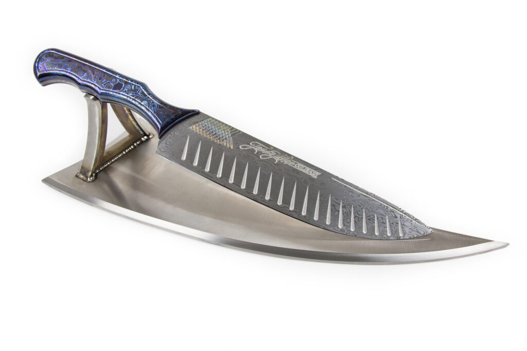 Handcrafted Damascus steel knife by Jesse James on display stand
