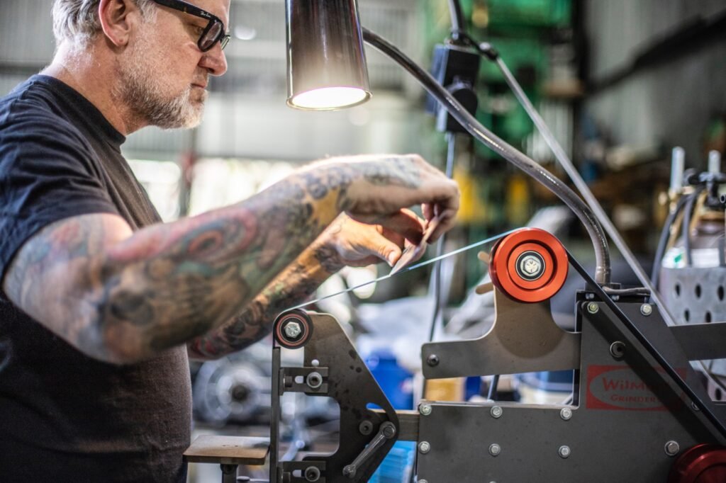 Jesse James shaping knife blade on belt grinder machine