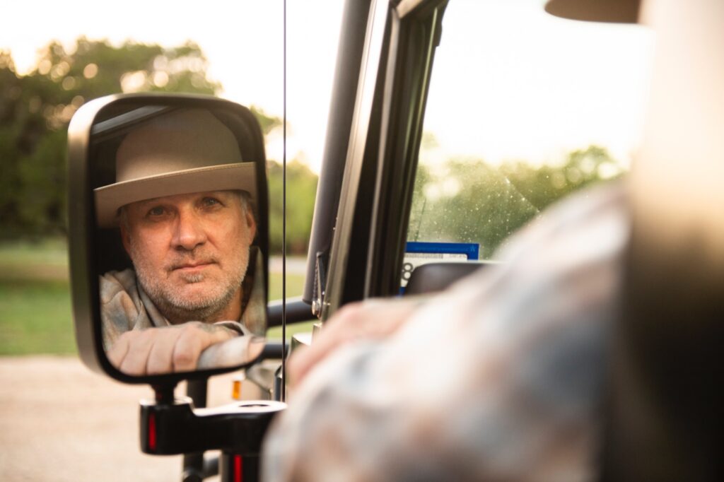 Reflection portrait of Jesse James in vehicle side mirror