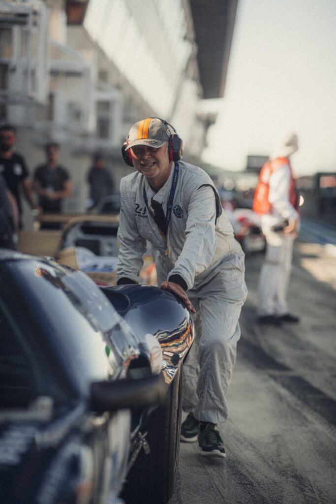 Man pushing a vintage race car in pit lane at Classic Le Mans