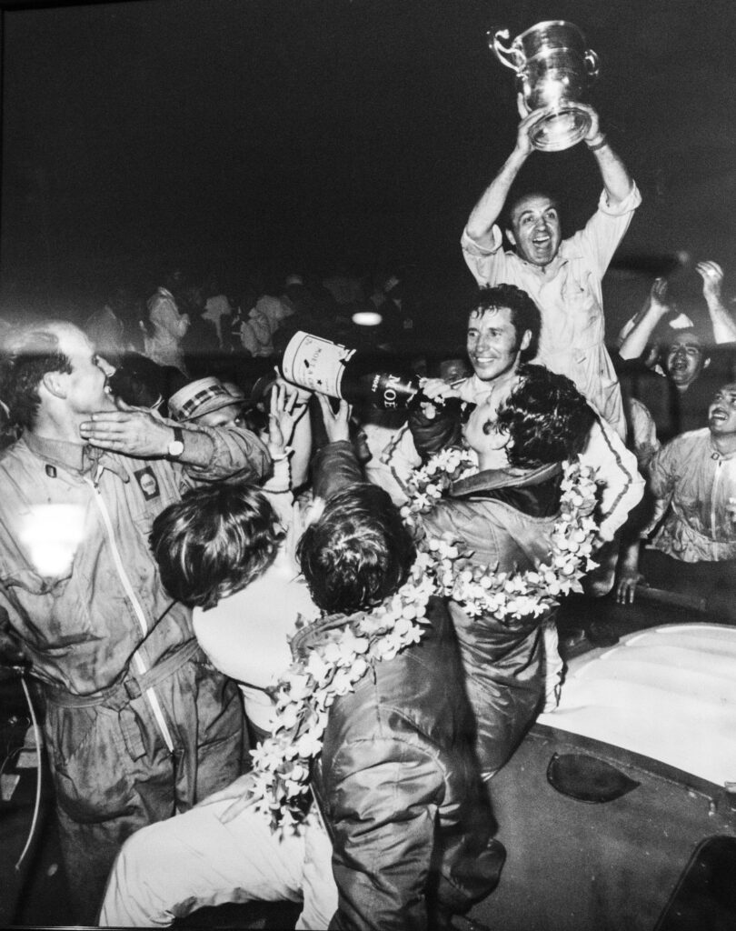 Mario Andretti celebrating with a crowd in an archival racing photo