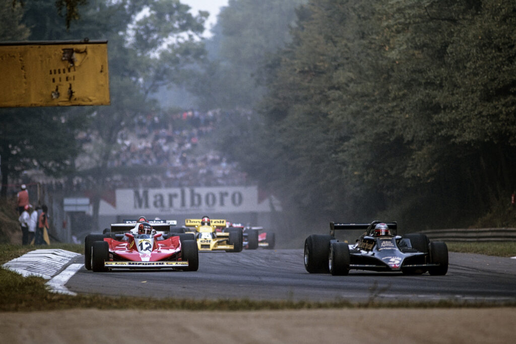Mario Andretti in Formula One race action with Ferrari and Lotus cars nearby