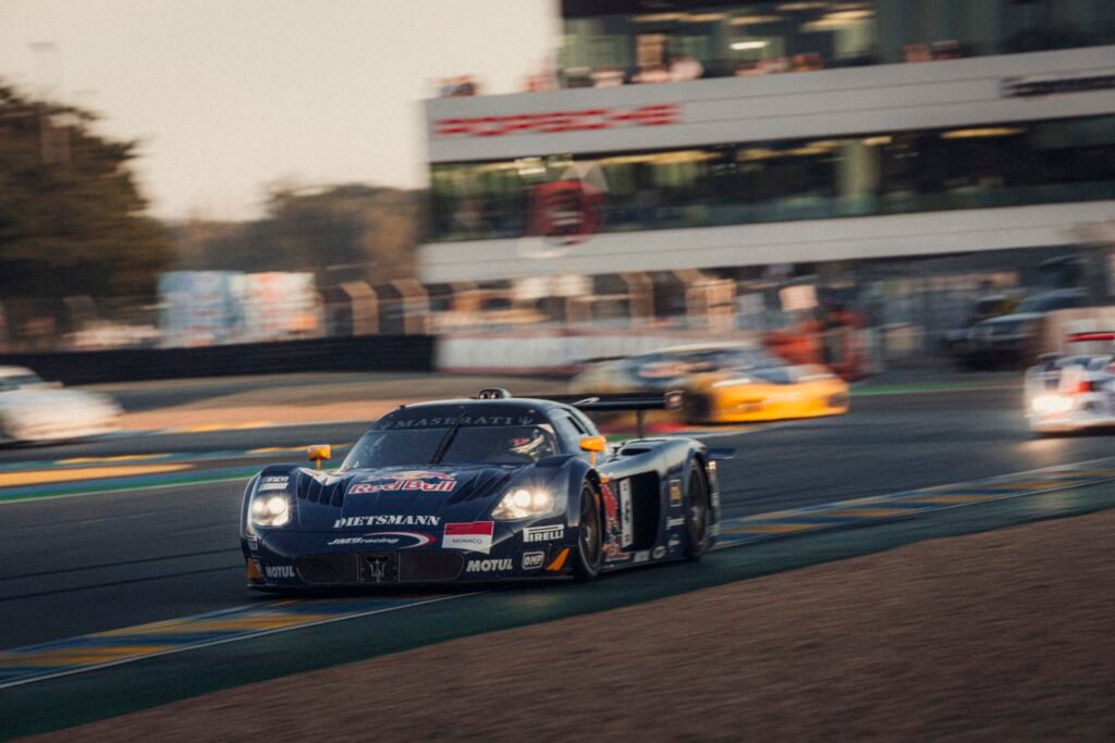 Black Maserati MC12 GT1 race car cornering at speed with motion blur at Le Mans Classic