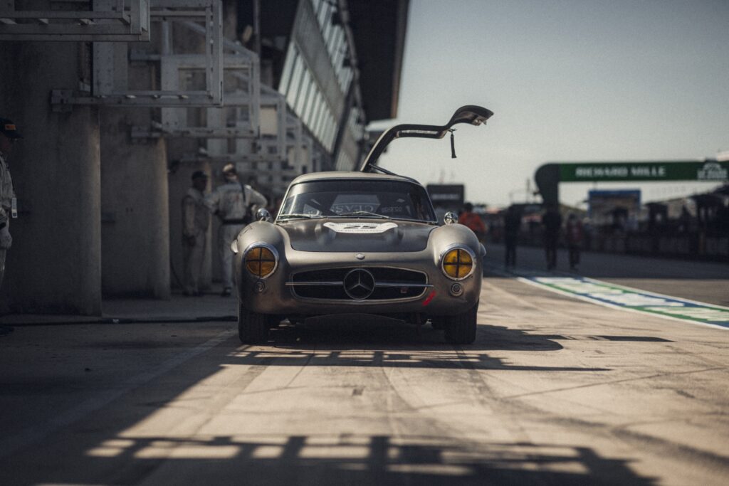 Mercedes race car with gullwing door open in pit lane at Peter Auto Classic Le Mans