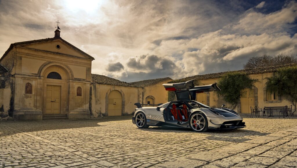 Pagani hypercar with signature gullwing doors open in courtyard