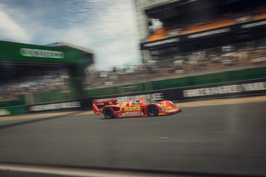 Red historic prototype race car driving at speed at Le Mans Classic, organised by Peter Auto