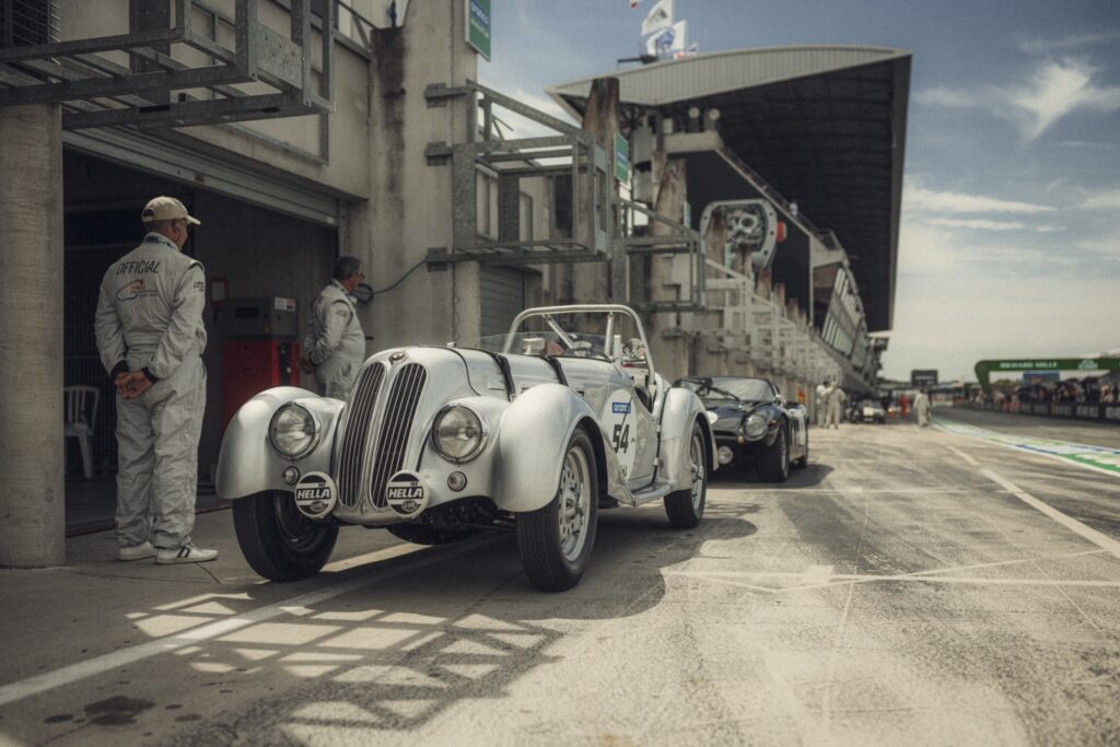 Vintage open-top roadster race car waiting in the pit lane at Le Mans Classic, organised by Peter Auto