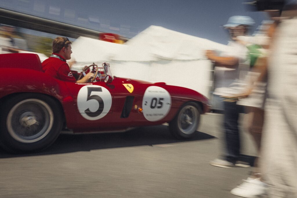Red vintage race car driving past spectators in the paddock at Classic Le Mans