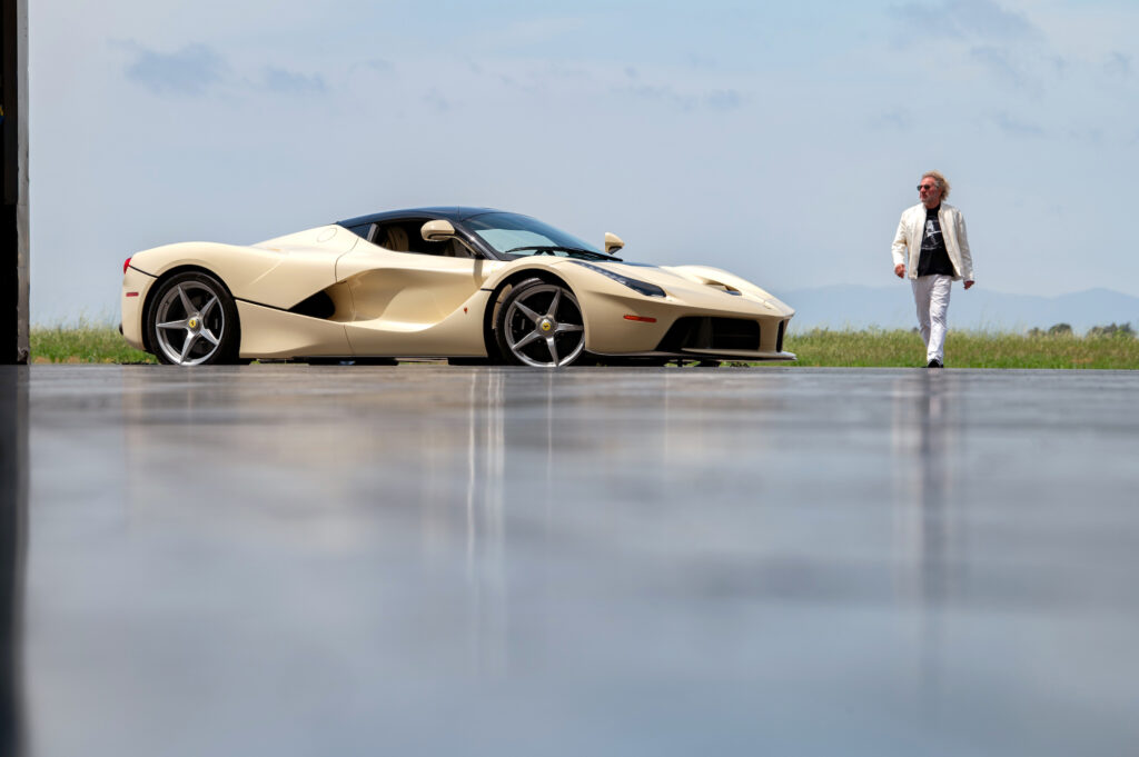 Sammy Hagar standing beside Ferrari LaFerrari on runway.