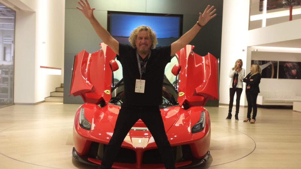 Sammy Hagar beside a red Ferrari LaFerrari at Ferrari factory.