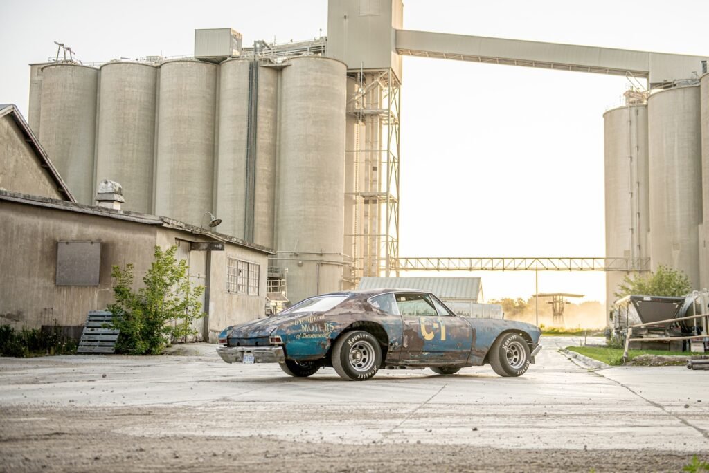Side profile of rusted 1968 Chevrolet Chevelle race car near concrete silos