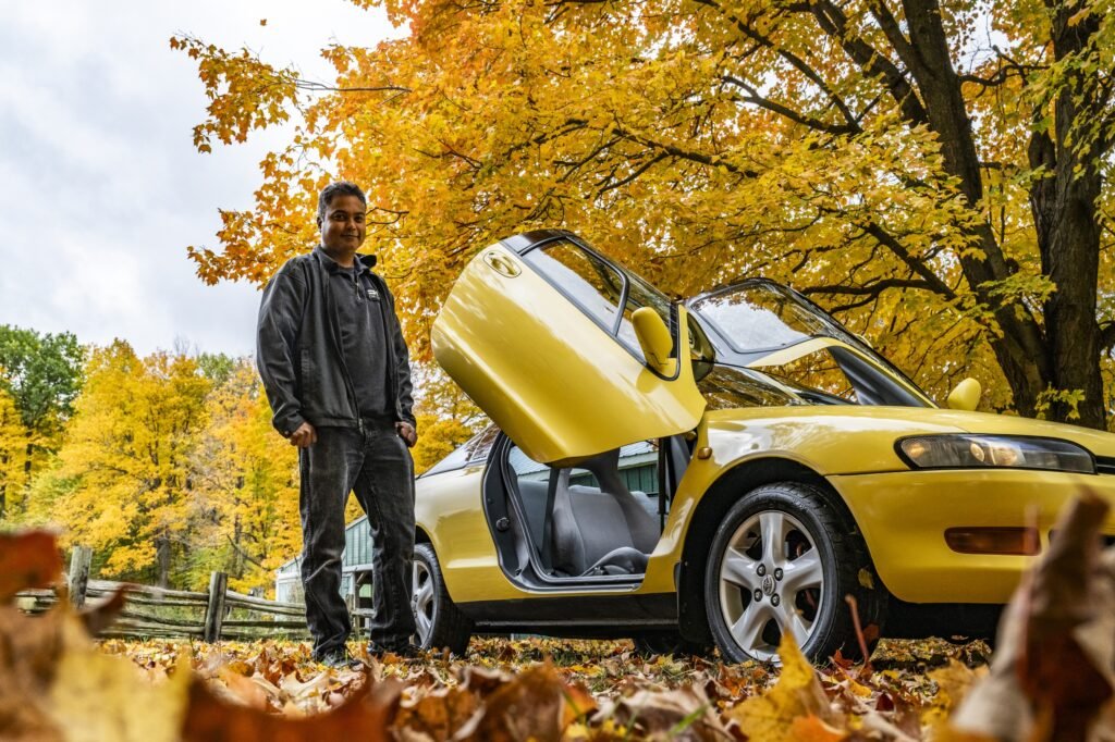 Person standing beside yellow Toyota Sera side view