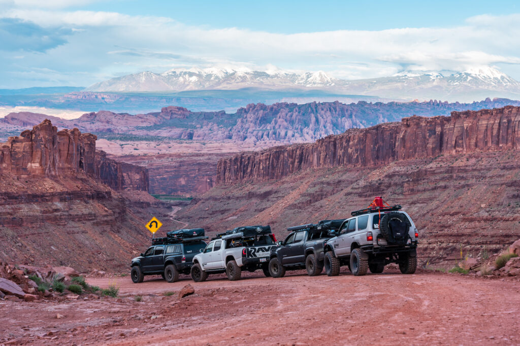 Overland convoy of Toyota trucks parked along a red rock canyon road in the American Southwest