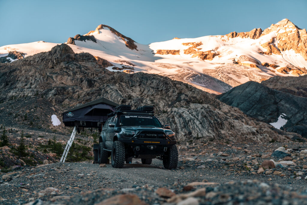 Toyota Tacoma overland build with rooftop tent deployed beneath glaciated alpine peaks