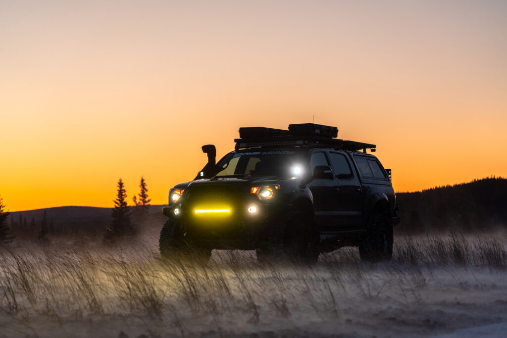 Toyota Tacoma overland build illuminated at sunset with auxiliary lighting