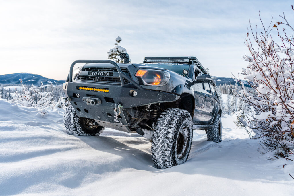 Toyota Tacoma driving through deep snow on a winter trail