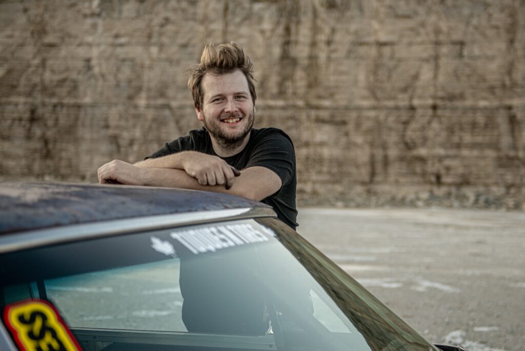 Portrait of Zack Gottvald leaning on roof of vintage race-prepped Chevrolet Chevelle