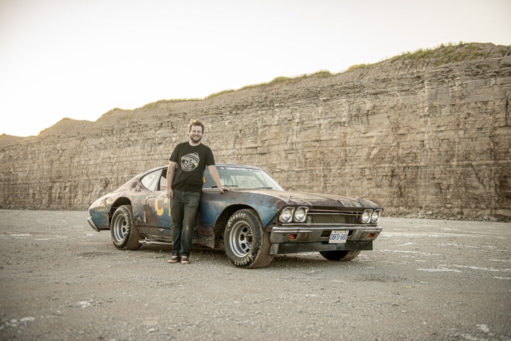 Zack Gottvald standing beside weathered 1968 Chevrolet Chevelle race car in quarry